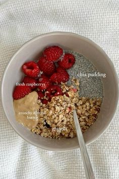 a bowl filled with oatmeal and raspberries next to a spoon