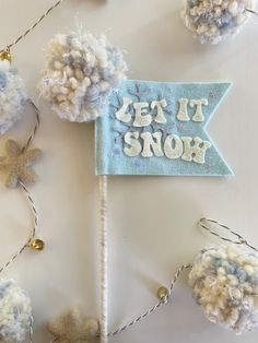 a sign that says let it snow with pom - poms on the side