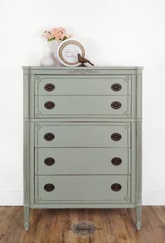 an old dresser is painted green and has drawers with knobs on the bottom, along with a clock