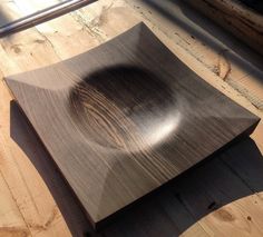 a wooden plate sitting on top of a wooden floor next to a window with sunlight streaming through it