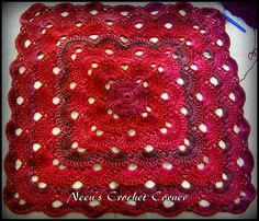 a red crocheted square with white dots on the edges and a flower in the center