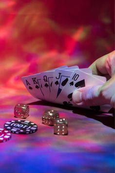 playing cards and dice on a table with colored lights in the background