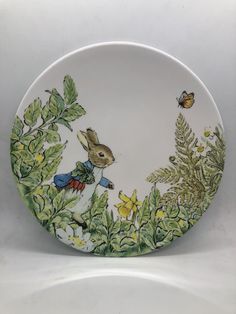 a plate with an image of a rabbit in the forest on it's side