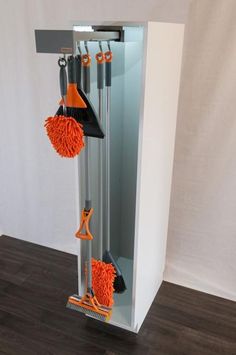 two brooms are hanging from the side of a cabinet