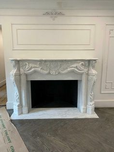 an empty fireplace with white paint on the mantle and wood flooring next to it