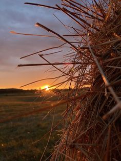 the sun is setting behind a hay bale