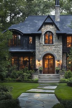 a stone house with lots of windows and steps leading up to the front door that lead into the yard