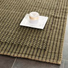 a white cup sitting on top of a table next to a brown and black rug