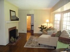 a living room filled with furniture and a fire place next to a window on top of a hard wood floor