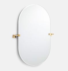 an oval mirror with two gold handles on the front and back of it, against a white background