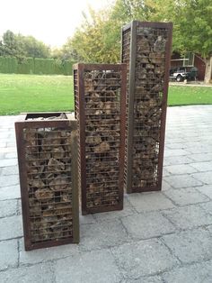 three metal boxes sitting on top of a stone floor next to grass and trees in the background