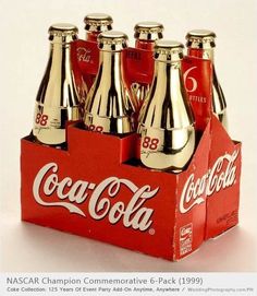 six coca - cola bottles in a red box with silver caps on top and bottom