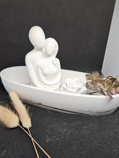 there is a small white sculpture in the shape of a man and woman sitting on a boat