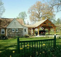 a green fence in front of a house with a covered porch and picnic area next to it