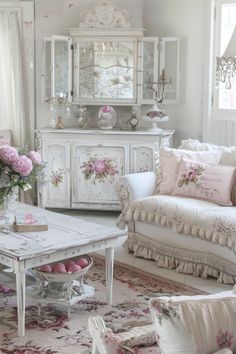 a living room with white furniture and pink flowers in vases on the coffee table