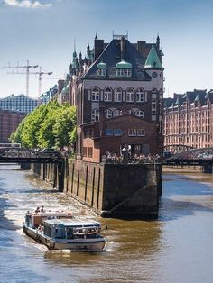 a boat is going down the river in front of some old buildings and tall buildings