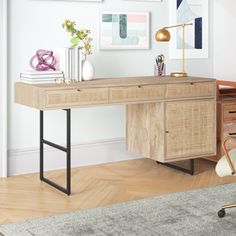 a wooden desk sitting in front of a wall with pictures on it and a chair next to it