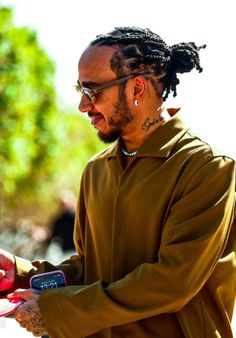 a man with dreadlocks is looking at his cell phone