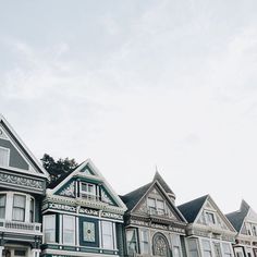 a row of multi - colored victorian homes on a cloudy day