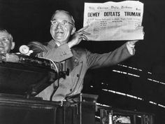 an old black and white photo of a man holding up a newspaper while standing next to another man