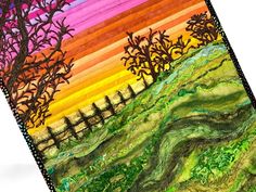 a quilted landscape with trees, grass and rainbow colors in the background on a white surface