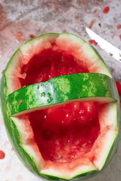 a watermelon cut in half with a knife next to it