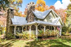 a house in the woods surrounded by trees and foliage with an american flag on the front porch