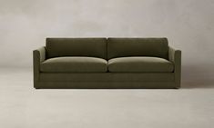 a green couch sitting on top of a white floor next to a wall with a gray background