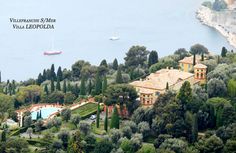 an aerial view of the villa and its surrounding gardens, with boats in the water