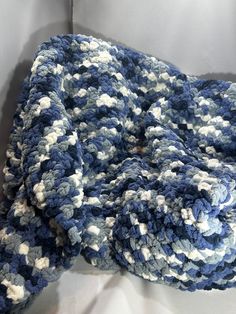 a blue and white crocheted blanket laying on top of a table