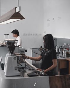 two people working in a coffee shop, one is using the espresso machine