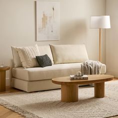 a living room with a white couch and coffee table in front of a painting on the wall