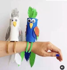 two paper birds sitting on top of each other next to a person's arm