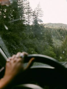 a person driving a car on a road with trees in the background