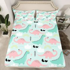 a bed with pink and blue dinosaurs on it, next to a potted plant