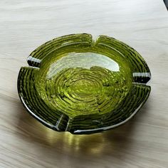 a green glass bowl sitting on top of a wooden table