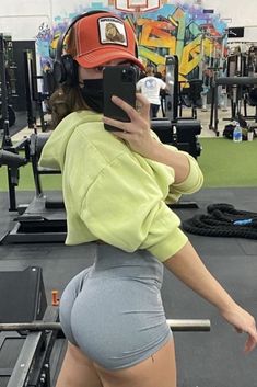 a woman in short shorts taking a selfie with her cell phone at the gym