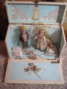 two dolls in a blue box on a table