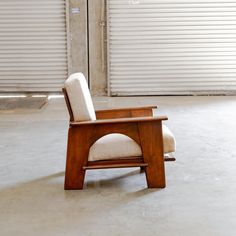 a chair sitting in the middle of a room with shutters on the wall behind it