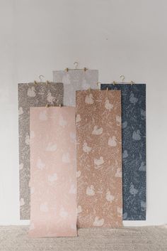 four different colored paper bags hanging from hooks on a white wall, each with an animal pattern