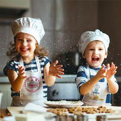 two young children in chef's hats and aprons are making dough with their hands