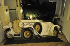 an old fashioned car is on display in a room with tile flooring and walls