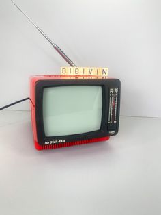 an old television sitting on top of a white table next to a pair of scissors