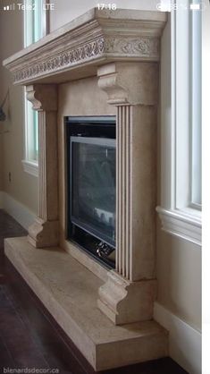 a stone fireplace with a tv on top of it in a room next to a window