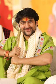 a man sitting down wearing a green outfit