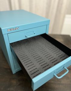 a blue filing cabinet sitting on top of a wooden table