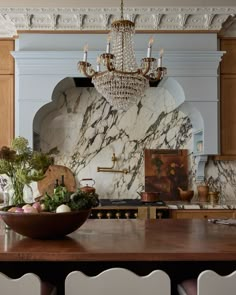 a bowl of fruit is sitting on a table in front of a chandelier