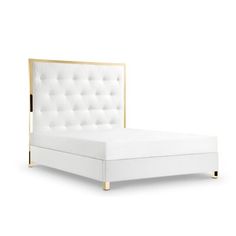 a white bed with gold trim and buttons