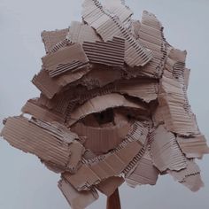 a sculpture made out of cardboard on top of a wooden stick with paper strips all over it