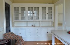 an empty room with white cabinets and chairs